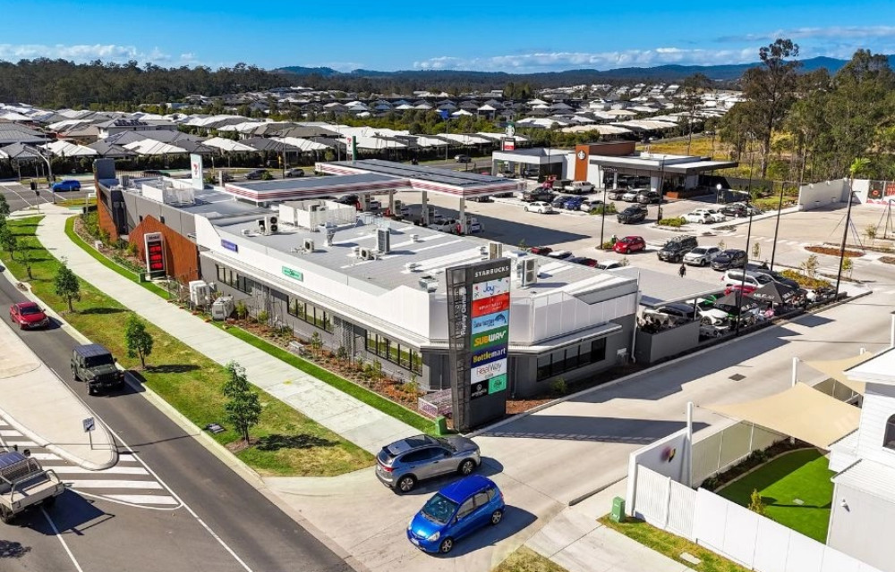 Artist impression of a contemporary retail and mixed-use precinct in south-east Queensland showing landscaped public areas, shops and surrounding infrastructure